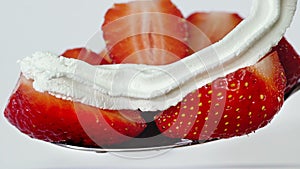 Close up half strawberry spoon dessert with whipping white cream