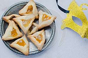 Close up Hamantashen cookies with apricot jam, masks on the table. Purim celebration concept. top view