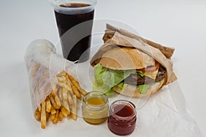 Close-up of hamburger, french fries, sauce and cold drink