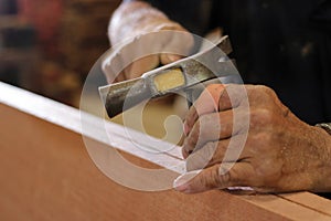 Close up hammer and nail using by carpenter on wooden board. Selective focus and shallow depth of field.