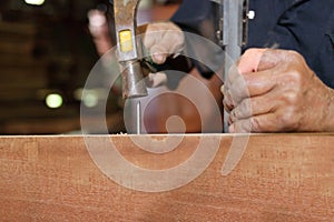 Close up hammer and nail using by carpenter on wooden board. Selective focus and shallow depth of field.