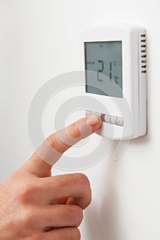 Close Up Of hand Adjusting Digital Central Heating Thermostat