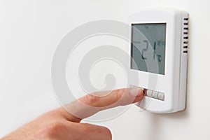 Close Up Of Hand Adjusting Digital Central Heating Thermostat Co