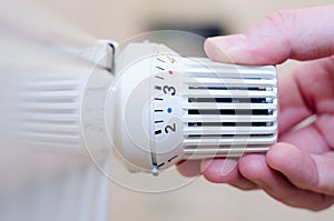 Close Up Of Hand Adjusting Heating Thermostat