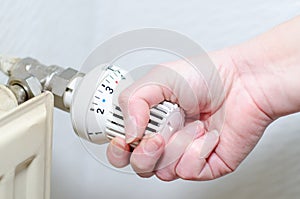 Close Up Of Hand Adjusting Heating Thermostat