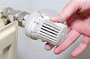 Close Up Of Hand Adjusting Heating Thermostat