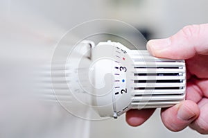 Close Up Of Hand Adjusting Heating Thermostat