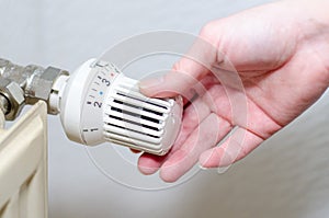 Close Up Of Hand Adjusting Heating Thermostat