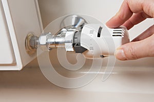 Close Up Of Hand Adjusting Radiator Thermostat