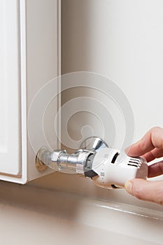 Close Up Of Hand Adjusting Radiator Thermostat