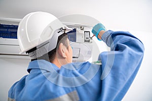 Close-up hand of Air technician service repairing and installs air conditioner on white wall. Service concept of an air