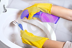 Close up of hand applying detergent and cleaning toilet with brush