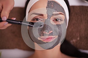 Close up of hand applying facial mask to woman face at beauty salon