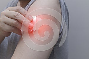 A close-up of a hand applying a nicotine patch to the upper arm. Represents Nicotine Replacement Therapy (NRT)