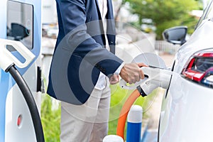 Close-Up hand of Asian man with EV charging station for electric car. Eco-friendly sustainable energy concept. EV car