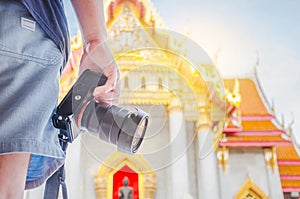 Close up hand asian man traveling backpacker holding camera at Wat Benchamabophit Dusitvanaram in Bangkok, Thailand