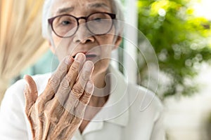 Close up of hand,asian senior woman checking breath,old elderly doing a bad breath test,foul mouth,strong unpleasant,smelling