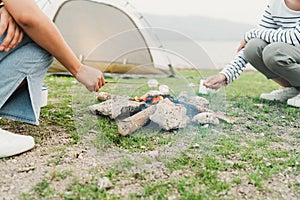 Close-up. Hand of asian woman grill marshmallow on bonfire in camping, picnic in campfire. Camping in vacation concept summer time