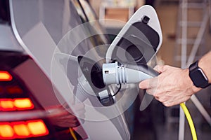 Close Up Of Hand Attaching Power Cable To Environmentally Friendly Zero Emission Electric Car