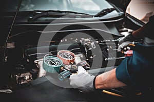Close up hand of auto mechanic using measuring manifold gauge check the refrigerant and filling car air conditioner for fix and