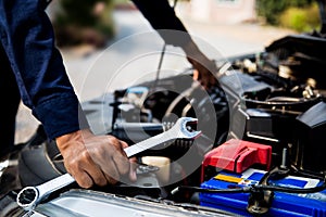 Close-up hand of auto mechanic using wrench to repair a car engine.