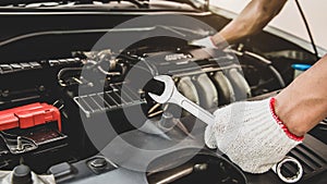 Close-up hand of auto mechanic using wrench to repair a car engine.