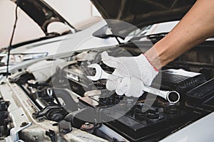 Close-up hand of auto mechanic using wrench to repair a car engine.