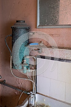 Close up of hand basin and oxidised water heater in derelict house built in 1930s deco style, Rayners Lane, Harrow UK