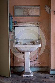 Close up of hand basin and oxidised water heater in derelict house built in 1930s deco style, Rayners Lane, Harrow UK