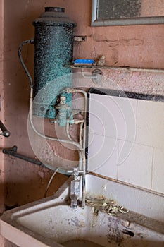 Close up of hand basin and oxidised water heater in derelict house built in 1930s deco style, Rayners Lane, Harrow UK