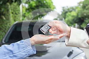 Close up hand Beautiful young woman car salesman holding car keys and handing it to Asian female customer