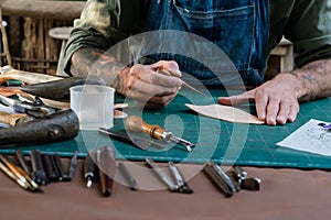 Close-up hand being picked up selection handcrafted leathercraft tools every step way, hand mechanic picks up variety