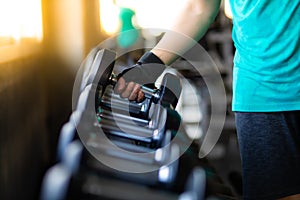 Close up hand bodybuilder lifting dumbbell weights at fitness gym. Exercise is the Lifestyles of healthy