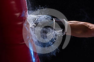 Close-up hand of boxer at the moment of impact on punching bag over black background