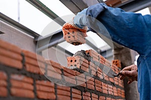 Close up hand of Bricklayer worker installing brick masonry on exterior wall on construction site