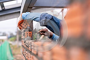 Close up hand of Bricklayer worker installing brick masonry on exterior wall with trowel putty knife on construction site