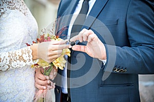 Close-up. Hand of bride and groom. Bride and groom hold hands. Focus on the rings. Bouquet in hand