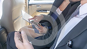 Close up on hand of business people using tablet and laptop during a trip in back seat car with paper file agreement contract