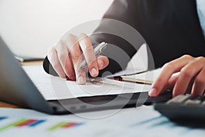 close-up hand of businessman analyzing investment chart on paperwork with laptop in office. concept finance and accounting