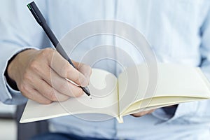 Close up hand of businessman holding pen and notebook, Writing something idea on note or check list