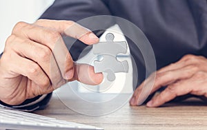 Close up hand of businessman holding two pieces of jigsaw puzzle