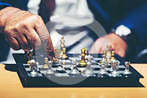 Close up hand of businessman moving chess figure in competition success play and thinking for management and planning work