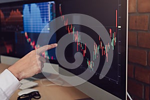 Close up of hand businessman pointing graph and analysis stock market on computer in office