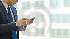 Close up hand of businessman using mobile phone near office wind