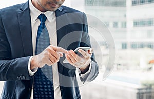 Close up hand of businessman using mobile phone near office wind