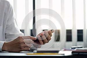 close up hand of businessman using mobile phone at office building, online business concept.