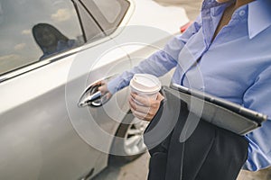 Close-up of the hand, Businesswoman opening the car door with coffee cup and laptop