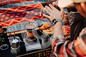 Close up hand of camper drip coffee in the camp, A man pouring water on coffee ground with filter.Drip coffee and camping