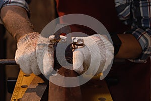 Close-up the hand of carpenter working hard while planing on wood with a manual wood planer or plane tool in workshop or carpentry