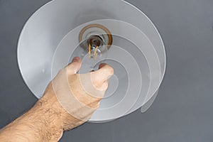 Close-up. A hand changes a light bulb in a stylish loft lamp. Spiral filament lamp. Modern interior decor